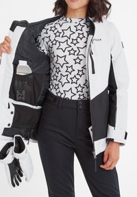 White and black insulated jacket with a zip, inner pocket, and gloves. Star-patterned top, black pants, and a sleek design.
