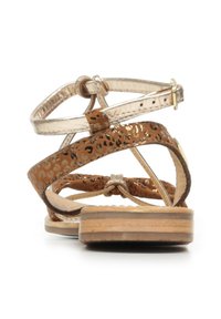 Sandaaltjes met bandjes van metallic goud en brown panterprintleer. Platte zool met gelaagd houten textuur. Verstelbare enkelband met gouden gesp.