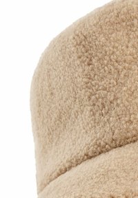 Beige fleecemuts met een zachte, textuur en een ronde top, met een horizontale naaddetail nabij de basis.