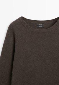 Ciemnobrązowy, długi rękaw, kaszmirowy sweter z okrągłym dekoltem typu crew neck, z widocznym prążkowanym kołnierzem i metką wewnątrz kołnierza.