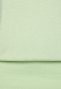 Hellgrüner Stoff mit glatter Textur, unten gefaltet. Einheitliche Farbe ohne Muster oder Akzente. Dünnes und dehnbares Material.