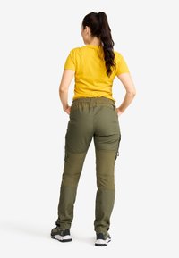 Olivgrön cargobyxor med elastisk midja, med sidofickor. Kombinerat med en enkel gul t-shirt och svarta sportskor.