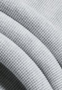 Heledad hall hallav väikese ruudustiku mustriga ja pehme materjali detailidega.