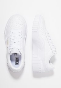 Zapatillas blancas con upper de cuero texturizado, perforaciones para transpirabilidad, cordones planos y una suela de goma gruesa con ranuras horizontales.