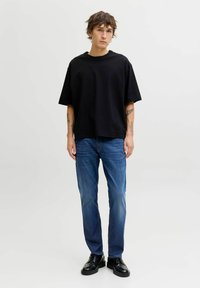 Mustast üleuuritud puuvillane T-särk, lühikeste varrukatega, sobitatud siniste teksapükstega ja mustade nöörkingadega. Lihtne disain ja mugav lõige.