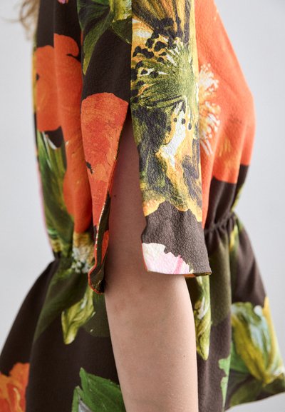Top cu imprimeu floral în culori vibrante de portocalie, verde și maron. Material moale, texturat, cu talie peplum și mâneci feliat.