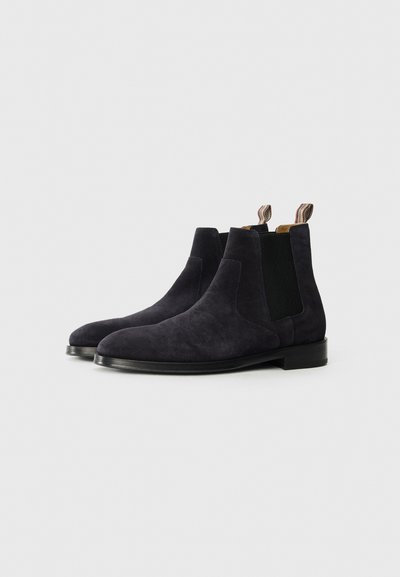 Botas Chelsea de ante negras con paneles laterales elásticos, punteras redondeadas y un tacón texturizado a contraste que incluye tiradores.