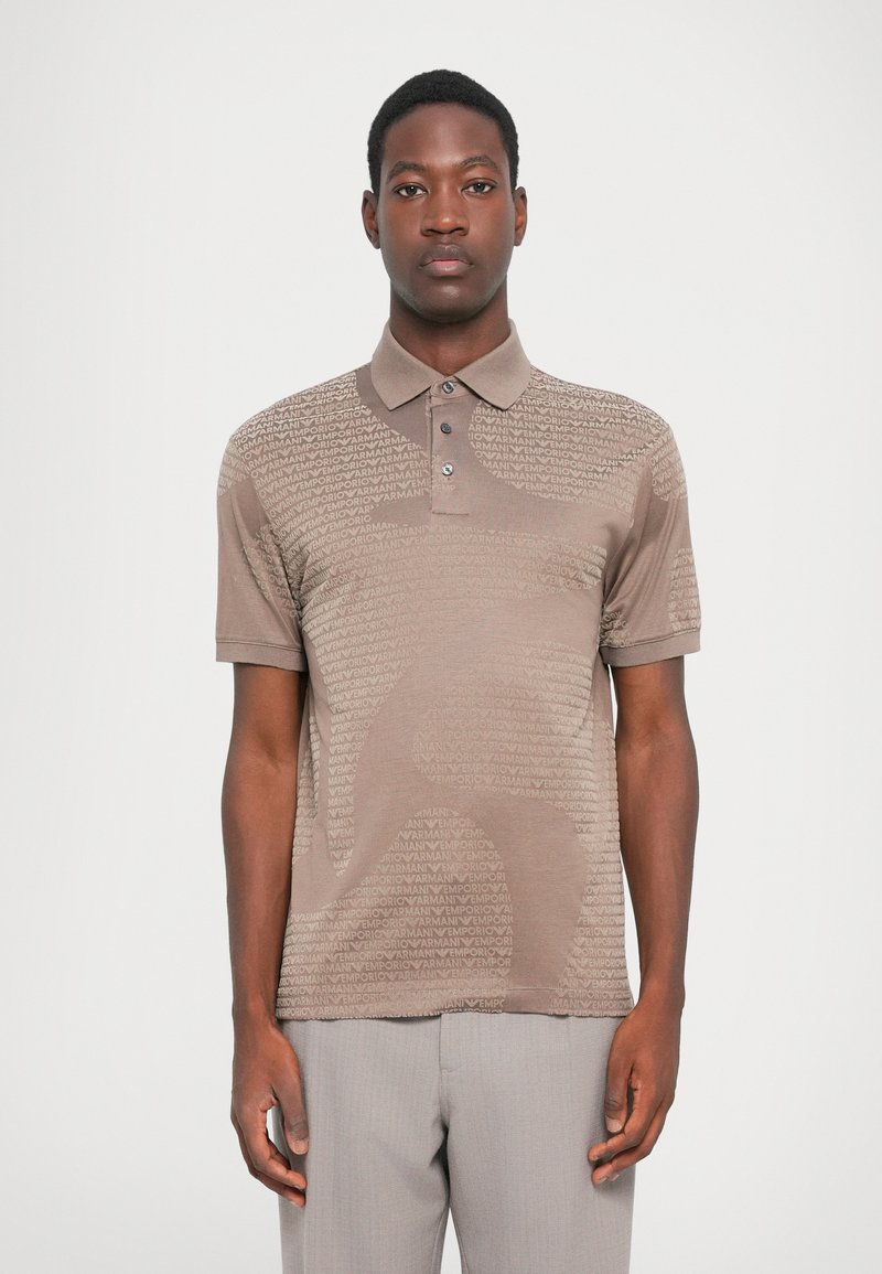 Brun polo skjorte med et teksturert mønster som har "EMPORIO ARMANI" tekst. Klassisk krage, tre knapper, korte ermer, slim fit.