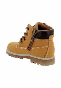Stivaletto beige con tomaia in pelle, dettagli marroni, occhielli in metallo e zip laterale. Suola in gomma con battistrada testurizzato per una presa migliore.