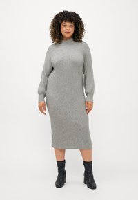 Vestido de malha canelada em cinza claro, com gola alta, mangas compridas e silhueta até à metade da perna, combinado com botas pretas de tornozelo.