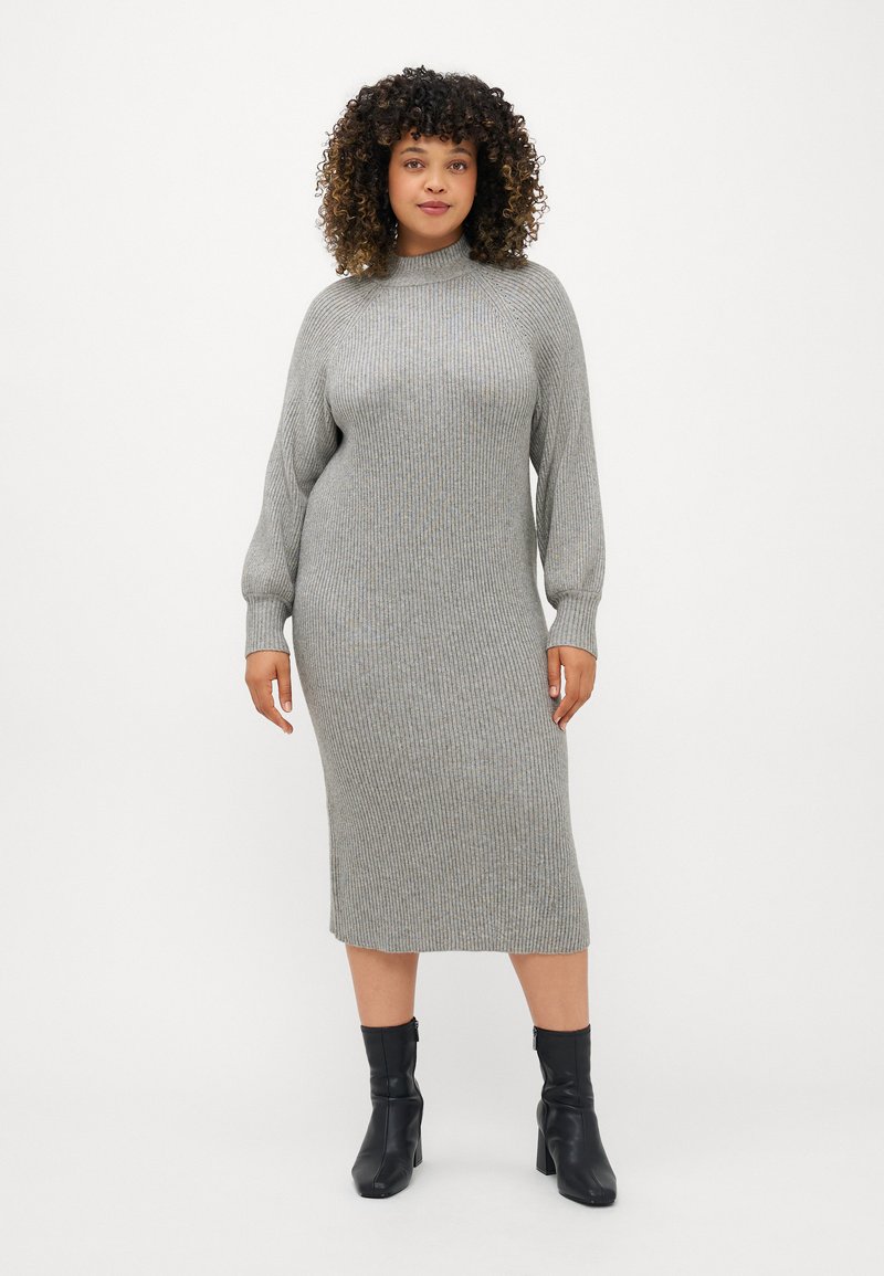 Vestido de malha canelada em cinza claro, com gola alta, mangas compridas e silhueta até à metade da perna, combinado com botas pretas de tornozelo.