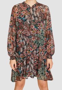 Vestido mini de paisley floral con mangas largas y elásticas. Hecho de una tela ligera y translúcida en tonos ricos de burdeos, verde y crema.