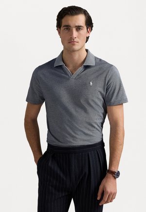 Sivý polo tričko s kontrastným svetlosivým golierom, krátkymi rukávmi a malým logom na hrudníku. Nosené s prúžkovanými nohavicami.