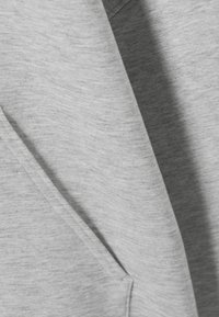 Gray sweatshirt with a soft, textured fabric. Features a prominent pocket and layered design, showcasing subtle variations in color.