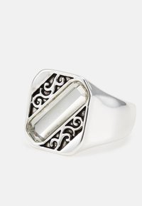 Anel de prata com uma pedra retangular e transparente, montada numa moldura de metal escurecido com um design intrincado e padrões em espiral.
