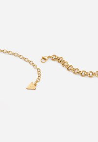 Gold chain bracelet featuring interlocking links, a triangular charm with embossed logo, and a lobster clasp closure.