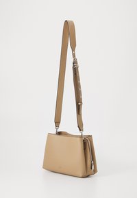 Borsa a spalla in pelle color cuoio con forma strutturata, tracolla regolabile e compartimento con zip. La superficie testurizzata aggiunge dettagli.