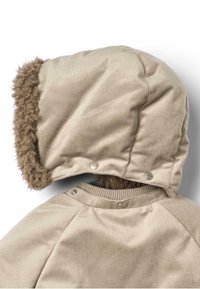 Beżowa kurtka z cordurowego materiału z futrzanym, brązowym kapturem. Posiada zatrzaski i prążkowany kołnierz. Miękka tekstura z widocznym prążkowanym wzorem.