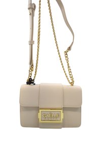 Borsa a tracolla beige con superficie testurizzata, hardware dorato, tracolla a catena e chiusura a patta con una vistosa placca centrale dorata.