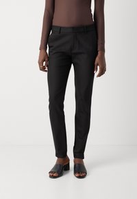 Černé elegantní kalhoty s úzkým střihem, hladkým materiálem a předními kapsami. V kombinaci s černými sandály na otevřenou špičku.