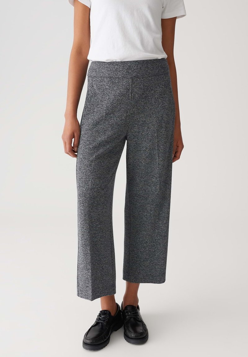 Pantaloni grigi a gamba larga realizzati in tessuto testurizzato, con vita alta e tasche, abbinati a scarpe stringate nere.
