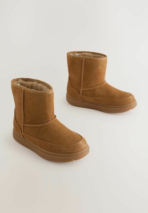 Braune Wildleder-Ankle-Boots mit einem weichen, plüschigen Innenfutter, runder Zehenform und einer Gummisohle. Einfache Nähte akzentuieren die Außenseite.