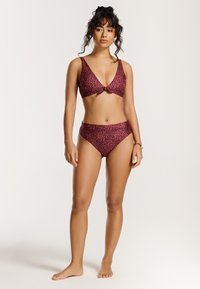 Bikini set featuring a deep V-neck top with a front bow and high-waisted bottoms. Material is textured with a maroon and pink speckled pattern.
