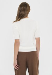 White short-sleeved sweater with a round neck, ribbed hem, and gentle puff sleeves, made from a smooth knit material.
