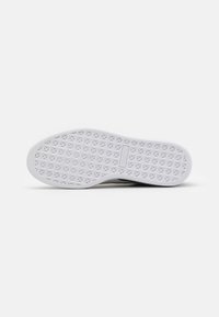 Semelle de chaussure en caoutchouc blanc avec un motif de bande de roulement en forme de losange et une zone rectangulaire pour le logo au centre.