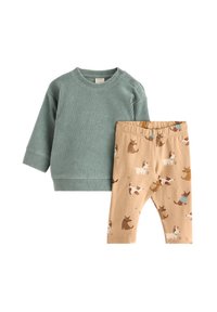 Grøn, ribbet langærmet bluse parret med beige leggings med hundemønster. Blødt stof med elastisk talje for komfort.