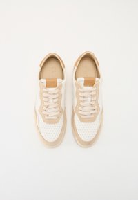 Beige und weiße Sneakers mit perforierten Details, Schnürdesign und einem hellbraunen Lederakzent an der Ferse. Weicher Stoff und minimalistischer Stil.