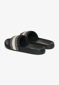 Chanclas negras con dos correas anchas que presentan un patrón trenzado en blanco y negro. Plantilla de textura suave y suela de goma.