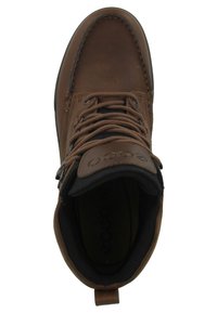 Bota de cuero marrón con forro de tela negra, puntera redonda, diseño con cordones y una pestaña en el talón. Presenta un logotipo embosado en la lengüeta.