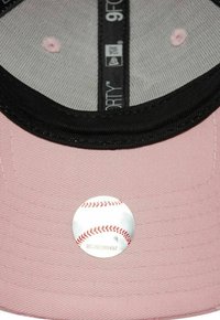 Rosa Baseballkappe mit flachem Schirm, ausgestattet mit einem silbernen Aufkleber mit einem Baseball-Motiv auf der Unterseite. Schwarze Umrandung entlang des Schirms.