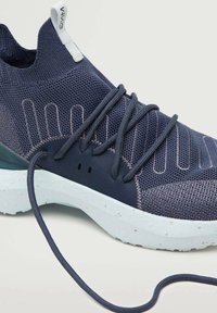 Chaussure de sport bleu marine avec une tige en maille, des détails texturés, des lacets élastiques et une semelle en caoutchouc claire avec des accents tachetés.