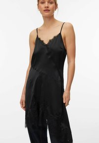 Robe nuisette en satin noir avec bordure en dentelle au niveau du décolleté et de l'ourlet. Dispose de fines bretelles et d'une coupe décontractée. Texture lisse, design élégant.