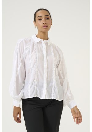 Weißes Button-Down-Hemd aus einem transparenten, leichten Stoff. Verziert mit dekorativen Besätzen entlang der Nähte und voluminösen, gerafften Ärmeln.