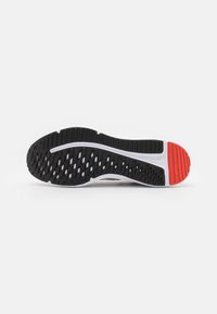 Schwarze und rote Sport-Schuhsohle mit strukturiertem Grip-Muster, ausgestattet mit einer weißen Zwischensohle und flexiblem Design für Traktion und Stabilität.