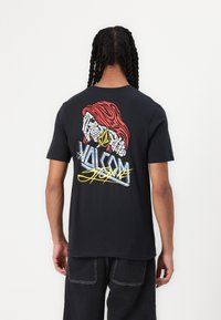 Black short-sleeve t-shirt featuring a colorful graphic of a stylized face and the "Volcom" logo on the back. Soft cotton material.