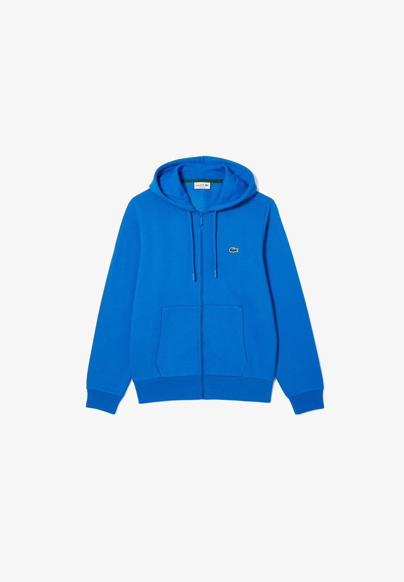 Sudadera con cremallera azul hecha de una mezcla de algodón. Cuenta con capucha ajustable, bolsillos frontales y un pequeño logo de Lacoste en el lado izquierdo del pecho.