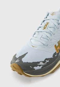 Αθλητικό παπούτσι σε ανοιχτό μπλε με γκρι λεπτομέρειες, υφή στο επάνω μέρος, πλέγμα και σόλα από καουτσούκ gum. Διαθέτει κομψό λογότυπο και σχεδιαστικό μοτίβο.