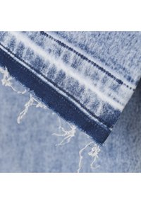 Jeanstyg med fransad fåll, som har ljusblå och marinblå nyanser. Det slitna tyget och de urblekta mönstren förstärker dess design.