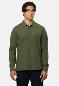 Hosszú ujjú olajzöld pólóing, gallérral, két gombos nyitással, és kicsi, hímezett logóval a bal mellen. Sima, texturált anyag.