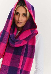 Różowo-fioletowy, w kratę szalik wykonany z miękkiego materiału, prezentujący duży fason do owinięcia wokół szyi z dekoracyjną krawędzią.