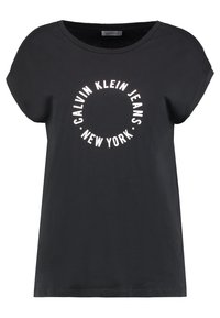 Czarny bawełniany t-shirt z krótkim rękawem, okrągłym dekoltem i białym okrągłym napisem "CALVIN KLEIN JEANS NEW YORK" na środku.