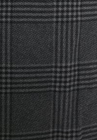 Tissu en laine noir et gris avec un motif classique tartan Glen comportant des carreaux grands et petits qui s'entrecroisent.