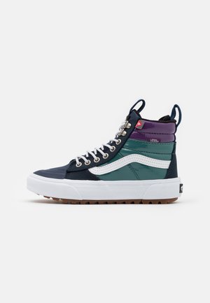 High-top sneakers featuring a navy textile upper, green and purple accents, white side stripe, metallic eyelets, and a white rubber sole.