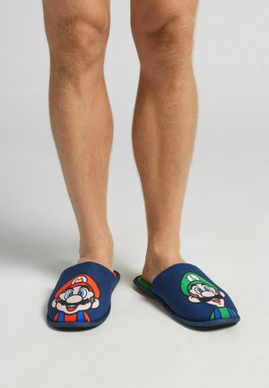 Blaue Stoffschuhe mit Mario- und Luigi-Designs, kontrastierender grüner Innenauskleidung und flachen Sohlen.