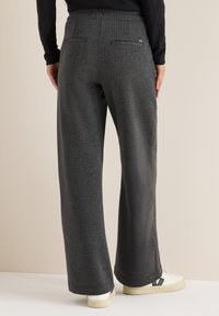Pantalones de pierna ancha grises con una tela texturizada, con cinturilla elástica y dos bolsillos traseros, combinados con zapatillas blancas.