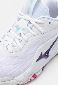 White athletic shoe with textured fabric, purple accents, and light blue details. Features a prominent logo and a thick, patterned sole.
